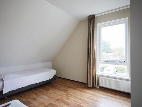 een slaapkamer met een bed en een groot raam bij Beautiful group accommodation, located in Zeeland in Heinkensand