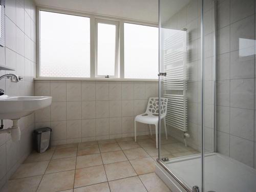 ein Badezimmer mit einer Dusche, einem Stuhl und einem Waschbecken in der Unterkunft Beautiful group accommodation, located in Zeeland in Heinkensand