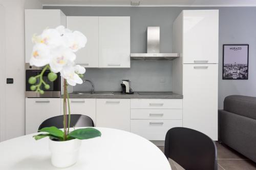 a white kitchen with a table with a vase of flowers at TURINHOMETOWN Residence Apartments in Turin