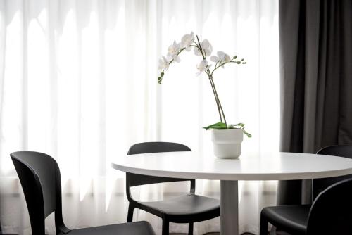 a white table with a vase with a plant on it at TURINHOMETOWN Residence Apartments in Turin