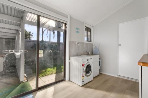 a laundry room with a washing machine and a window at The Beaches on Lakes - Big Family Holiday Home in Lakes Entrance