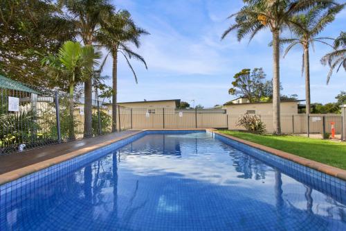 a swimming pool with palm trees in a yard at The Beaches on Lakes - Big Family Holiday Home in Lakes Entrance