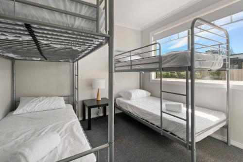 zwei Etagenbetten in einem Zimmer mit Fenster in der Unterkunft The Beaches on Lakes Cottage in Lakes Entrance