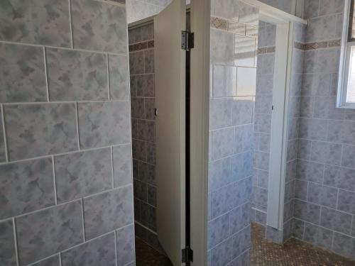 ein Bad mit einer Dusche und blauen Fliesen in der Unterkunft Parkes Hotel in Parkes