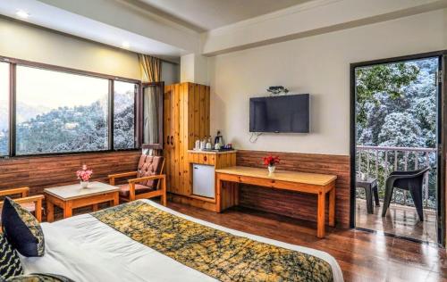 Schlafzimmer mit einem Bett, einem Schreibtisch und einem TV in der Unterkunft The Mountain Quail in Masuri