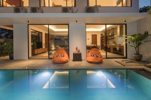 a house with a swimming pool in front of a house at Villa Daun 3 Canggu by Premier Hospitality Asia in Dalung