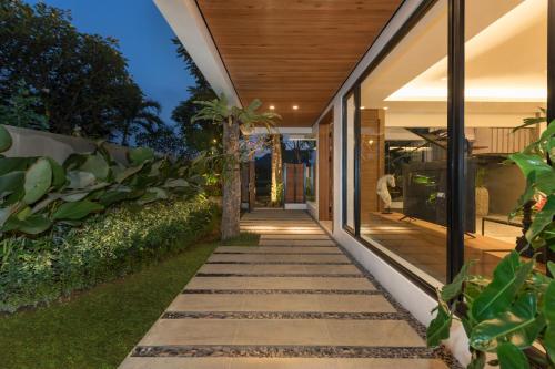 a walkway leading to a house with glass doors at Villa Daun 3 Canggu by Premier Hospitality Asia in Dalung