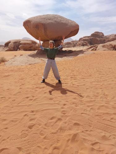 a man holding up a large rock in the desert at bedouin future camp in Wadi Rum