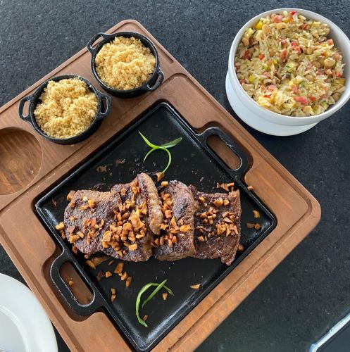 a plate of food with meat and a bowl of rice at Flat em Salinópolis no Salinas Premium Resort in Salinópolis