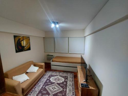 Habitación pequeña con sofá y cama en Alquiler Departamento Centro Mendoza Capital en Mendoza