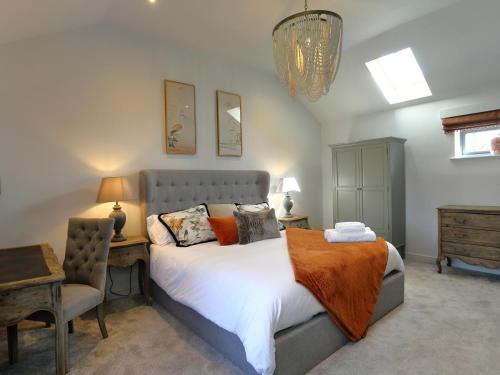 a bedroom with a bed and a chair and a chandelier at The Tyre Barn in Whitchurch