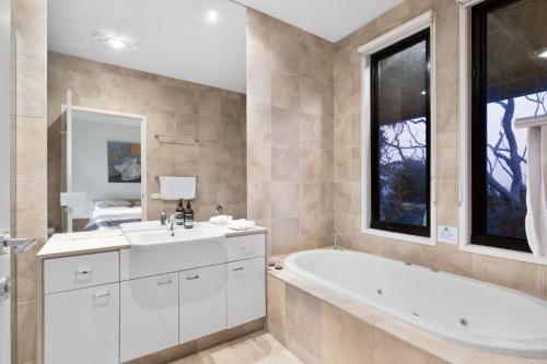 a bathroom with a tub and a sink at Skenes Beach House Stunning Ocean Views Amongst A Natural Bush Setting in Apollo Bay