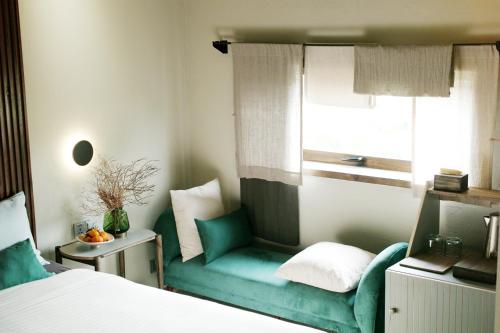 a bedroom with a green chair and a window at Kaia Gallery Hotel Hoi An in Hoi An