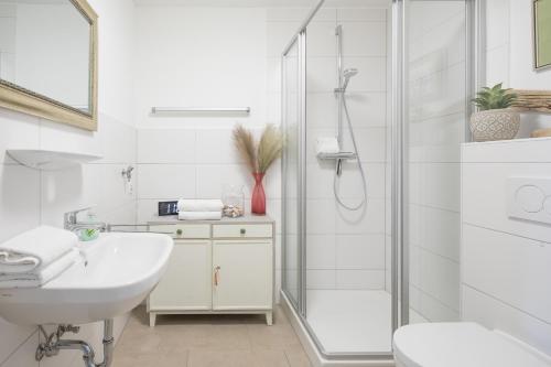 a white bathroom with a shower and a sink at Hafenmeister in Husum