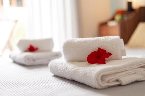 a pile of towels with a red flower on a bed at Dimeli Junior Apartment at the beach in Barbati