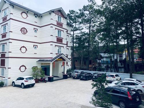 a large white building with cars parked in a parking lot at Khách sạn Hưng Việt (Măng Đen) in Kon Tum