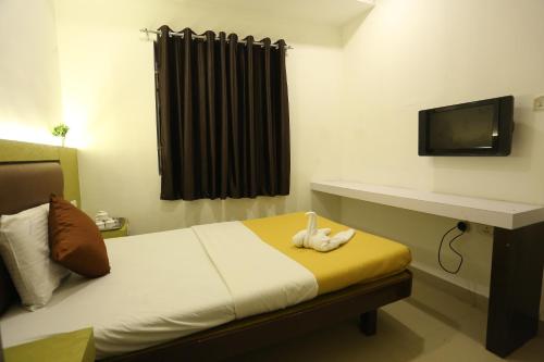a bedroom with a bed with a tv on a wall at GM Residency in Chennai