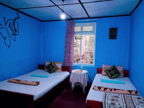 a blue room with two beds and a window at The 1964 Holiday bungalow in Ella