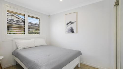 a bedroom with a bed with a picture on the wall at Vitamin Sea - Umina Beach in Ettalong Beach