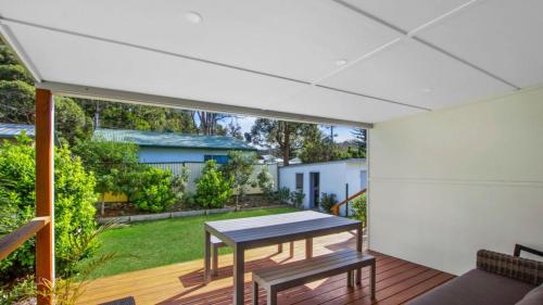 a patio with a table and benches on a deck at Lazy Days Seaside Cottage - Umina Beach in Umina