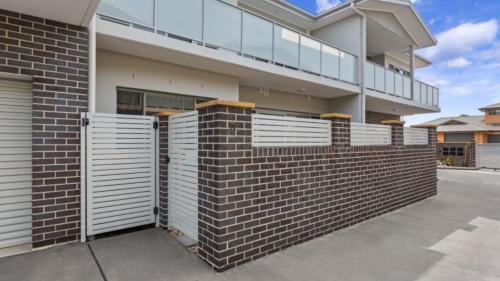 una casa de ladrillo con puertas blancas y una valla en Avani - Modern & Tranquil - Wifi, en Booker Bay