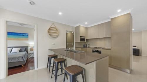 a kitchen with a counter and stools in a room at Avani - Modern & Tranquil - Wifi in Booker Bay