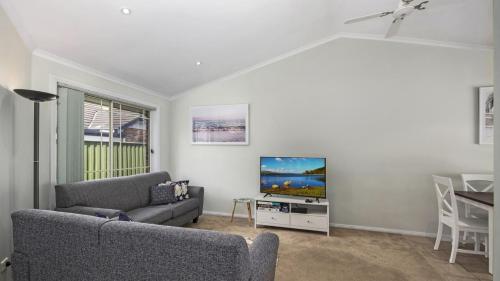 a living room with a couch and a flat screen tv at Beach Daze - Umina Beach Family Friendly in Umina