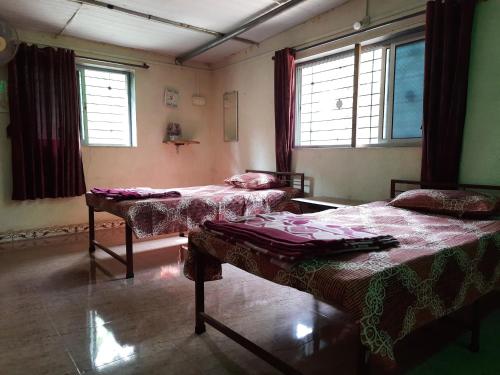 a room with two beds and two windows at Vidya Konkan Agro Tourism in Chiplun