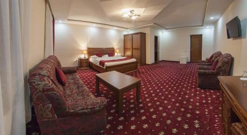 Gyumri Hotel في غيومري: غرفه فندقيه بسرير واريكه وطاولة
