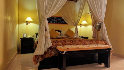a bedroom with a bed with a canopy at Masainn Hotel Kuta in Kuta