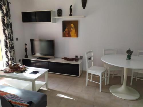 uma sala de estar com uma televisão e uma mesa e cadeiras em Sommer, Sonne, Strand und Pool! em Canyamel