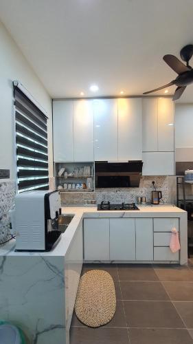 a kitchen with white cabinets and a counter top at Green Homestay Tangga Batu in Tangga Batu