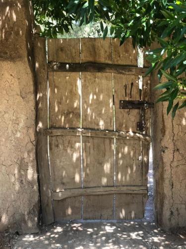 an old wooden door with the sun shining on it at Maison La Berberina in Goulmima