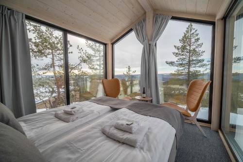 a bedroom with a large bed and large windows at Lapland View Lodge in Övertorneå