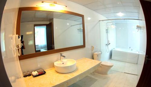 a bathroom with a sink and a mirror and a toilet at Khách Sạn Hoa Ban Trắng in Sơn La