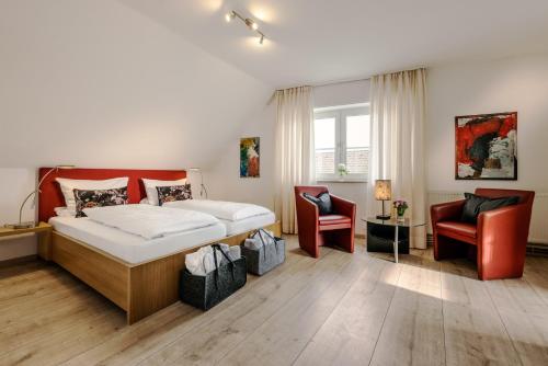 a bedroom with a bed and two chairs at Romantik Hotel Neuhaus in Iserlohn
