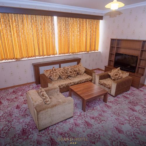 a living room with couches and a table and a fireplace at Grand Nakhchivan Hotel in Naxçıvan