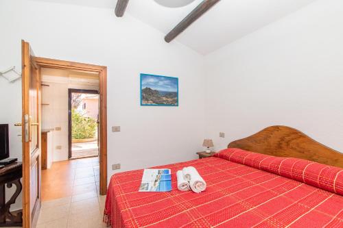 een slaapkamer met een bed met een rode sprei bij Giovanni in Capo Testa