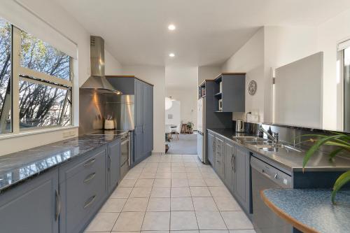 a large kitchen with gray cabinets and a window at APARTMENT 4A - By the Beach in Paraparaumu Beach
