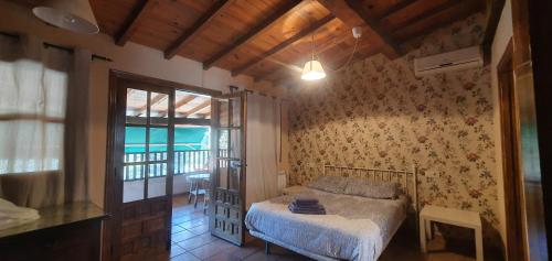 a bedroom with a bed and a room with a balcony at Casa Valle del Jerte, La Judería in Cabezuela del Valle