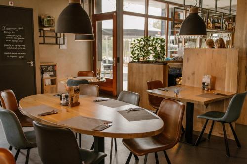 restauracja z drewnianymi stołami i krzesłami oraz tablicą w obiekcie De la Rue Vakantiesuites w mieście Sleeuwijk