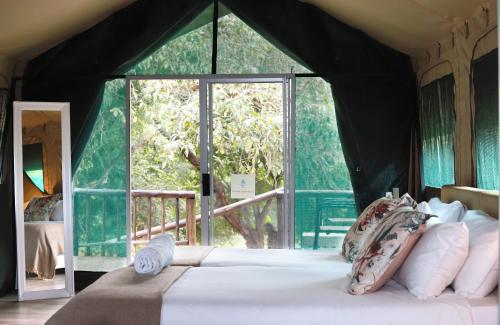 a bedroom with a large bed with a large window at Lions Rock Rapids - Luxury Tented Camp in Hazyview