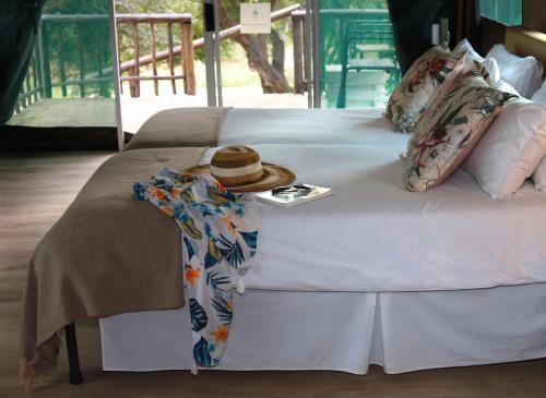 a hat sitting on top of a bed at Lions Rock Rapids - Luxury Tented Camp in Hazyview