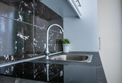 a kitchen with a sink and a black wall at Aegean Blue Seaview Studios in Agia Triada