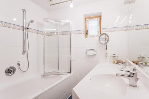 a white bathroom with a shower and a sink at Heimspitze - Alpenhotel & Wirtshaus in Gargellen