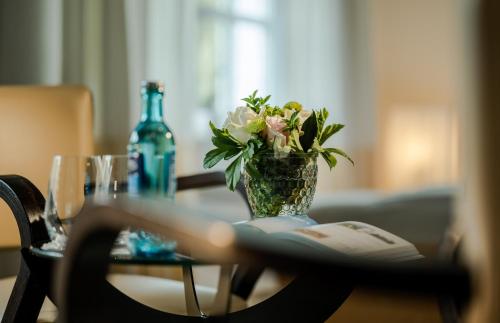 a vase of flowers on a table with a book at Romantik Hotel Neuhaus in Iserlohn