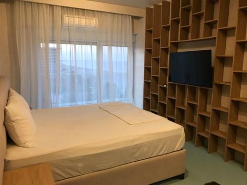 Un dormitorio con una cama y una pared con un televisor. en White Tower Mamaia Apartament 608, en Mamaia