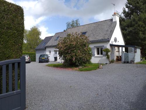 a white house with a car parked in the driveway at La chambre Lomen in Lauzach