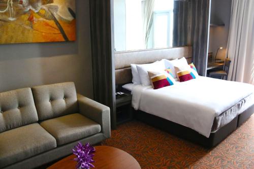 a hotel room with a bed and a couch at Aqueen Hotel Paya Lebar in Singapore