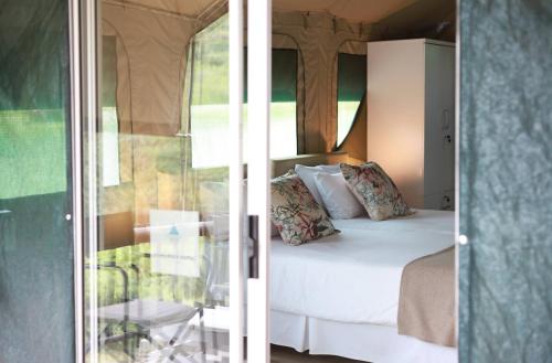 a bedroom with a bed and a sliding glass door at Lions Rock Rapids - Luxury Tented Camp in Hazyview